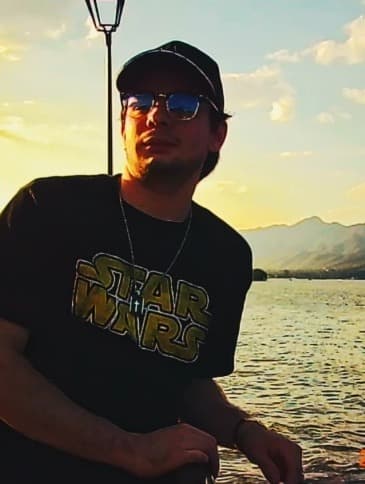 Hombre con gorra y lentes al atardecer frente al mar