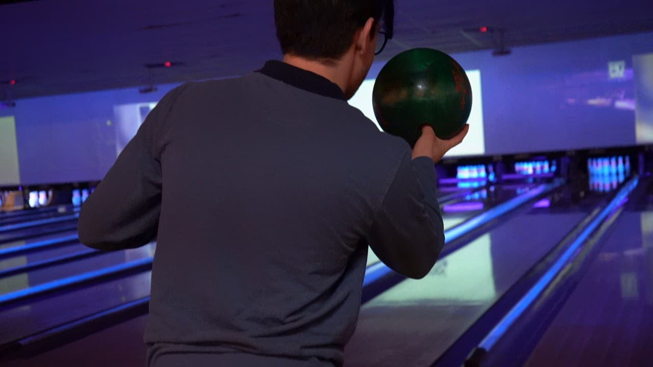 Hombre de espaldas con una bola de boliche bajo luz azul
