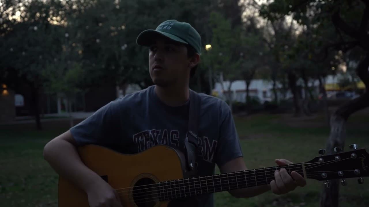 Guitarrista con gorra tocando en un parque al anochecer