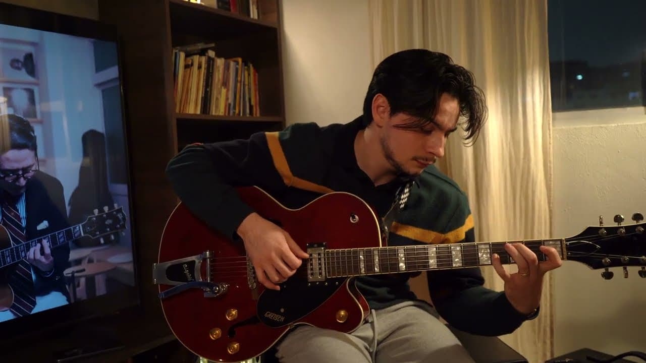 Guitarrista tocando una guitarra roja junto a un librero