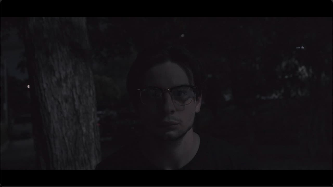 Retrato en penumbra de un hombre con lentes entre árboles
